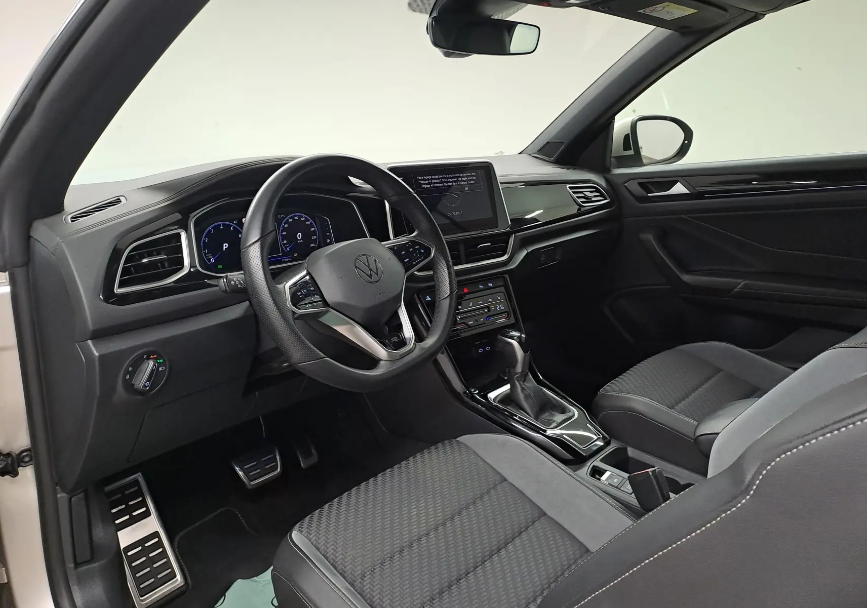 Vue intérieure côté conducteur du Volkswagen T-Roc Cabriolet 2022, tableau de bord noir et volant multifonction.