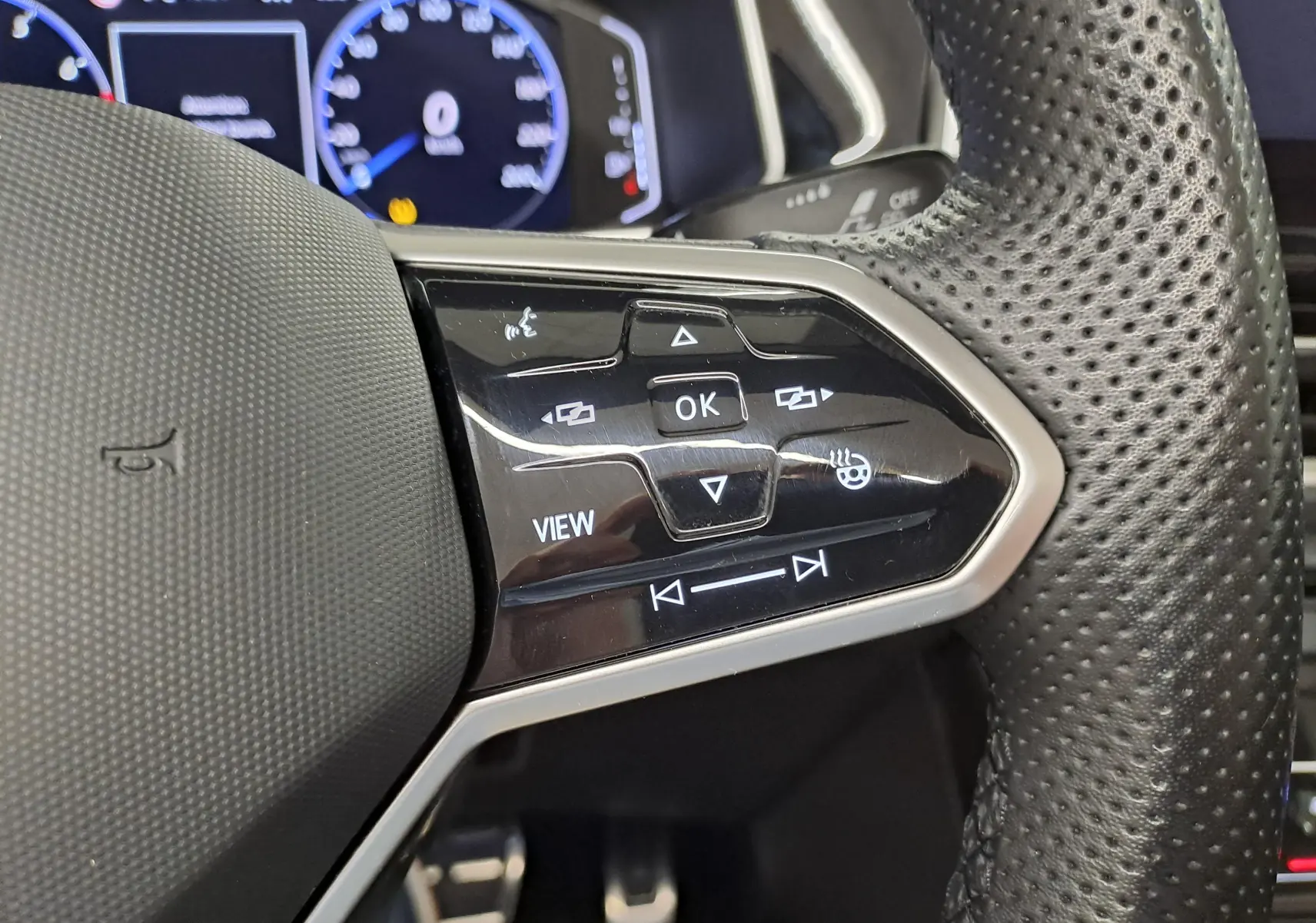 Gros plan sur les commandes du volant en cuir perforé du Volkswagen T-Roc Cabriolet gris ivoire, version R-Line 2022.