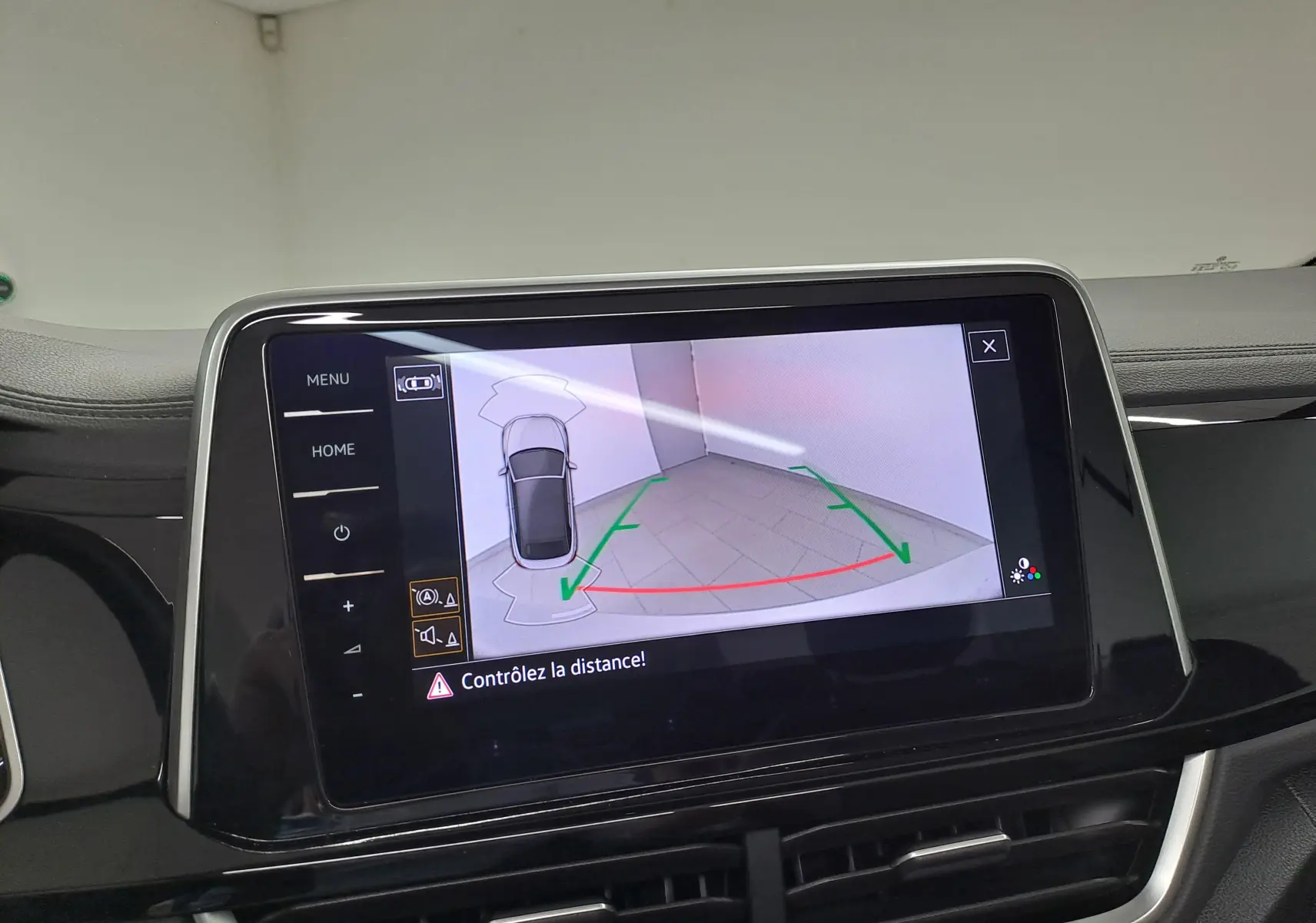 Écran tactile intérieur du Volkswagen T-Roc Cabriolet montrant la caméra de recul avec lignes de guidage vertes et rouges.