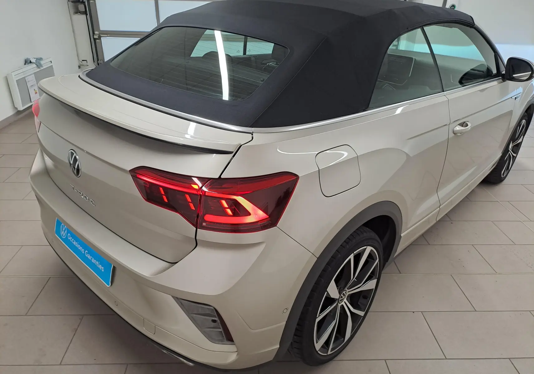 Vue 3/4 arrière droite du Volkswagen T-Roc Cabriolet gris ivoire avec capote noire et jantes alliage 19 pouces Misano.