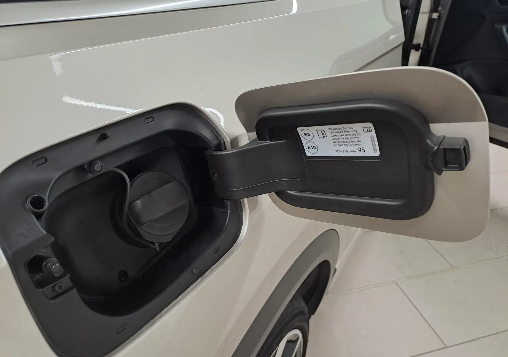 Gros plan sur la trappe à carburant côté gauche du Volkswagen T-Roc Cabriolet gris ivoire avec capote noire.