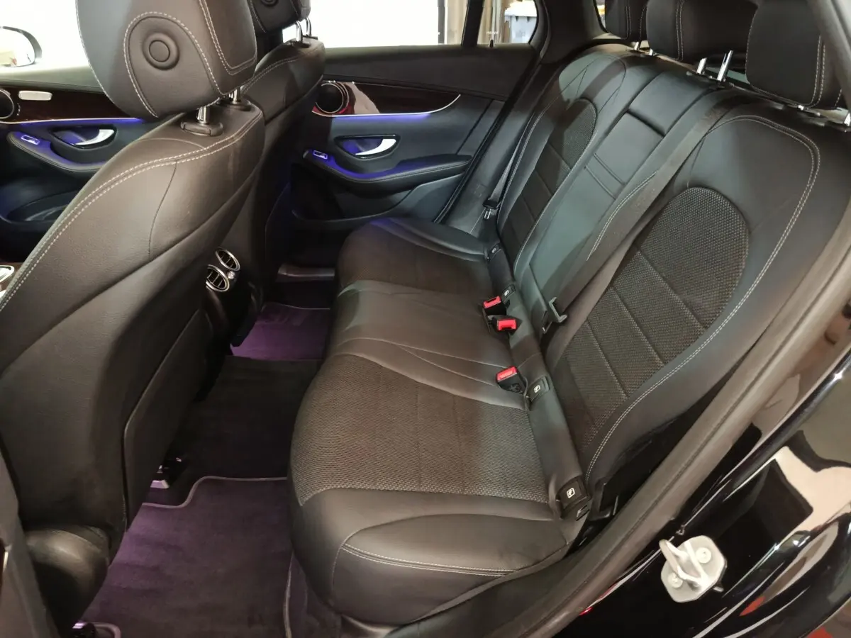 Vue intérieure côté droit des sièges arrière en cuir noir du Mercedes GLC 300 e Business Line 2020 avec éclairage d'ambiance violet.