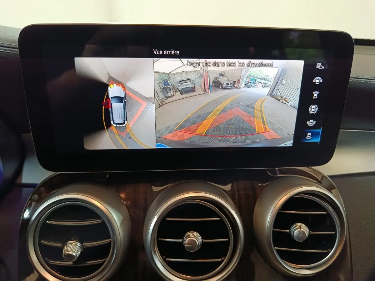 Écran tactile intérieur du Mercedes GLC 300 e Business Line affichant la caméra de recul et l'aide au stationnement.