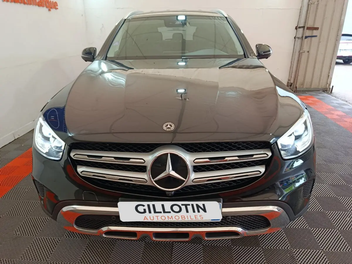 Vue frontale d'un Mercedes GLC 300 e Business Line 4Matic noir avec calandre chromée et phares LED allumés.