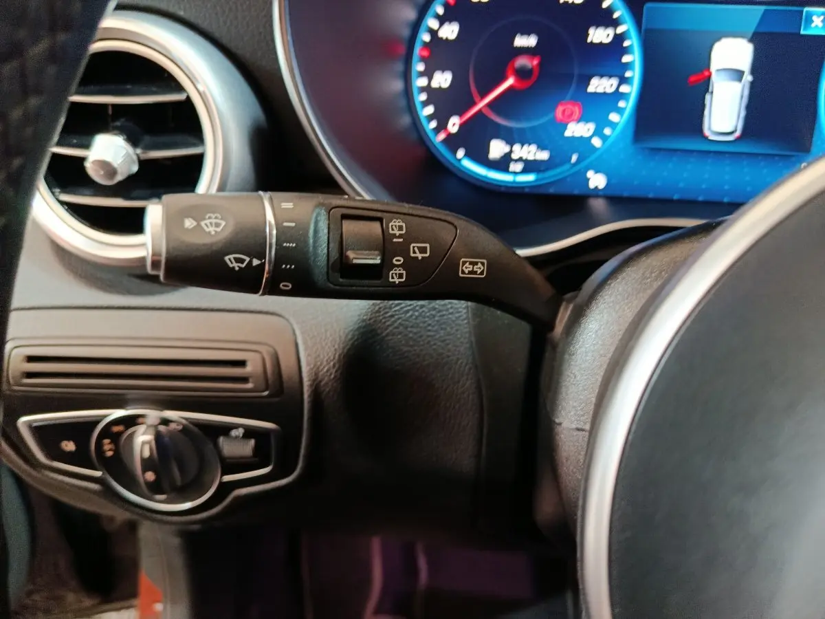 Gros plan sur la commande d’essuie-glace et tableau de bord numérique bleu d’une Mercedes GLC 300 e Business Line noire.