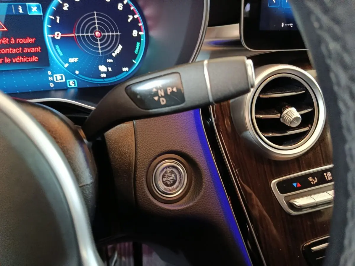 Gros plan intérieur sur le tableau de bord noir du Mercedes GLC 300 e, montrant le bouton démarrage et la commande de boîte automatique.