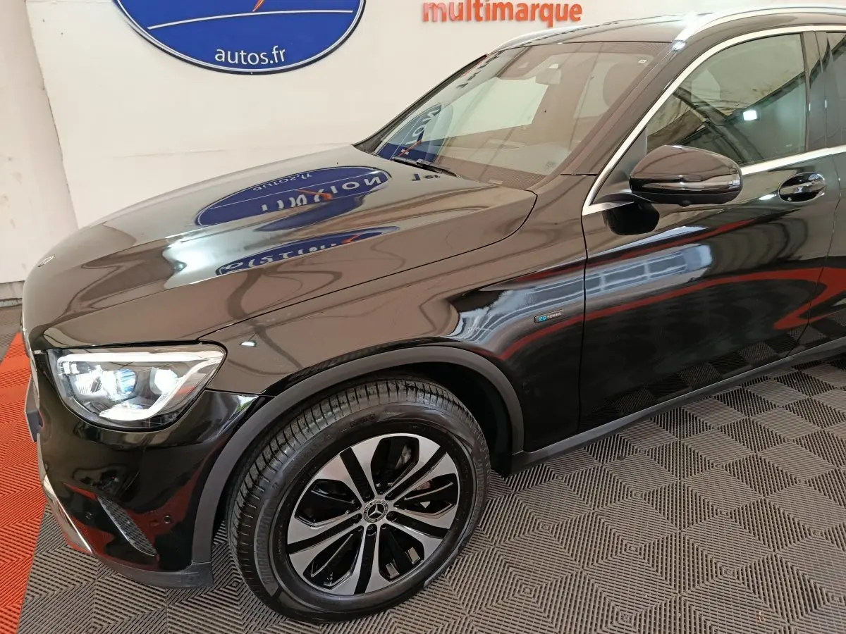 Vue 3/4 avant droit d'un Mercedes GLC 300 e Business Line noir brillant avec jantes alliage et badge hybride sur aile avant.