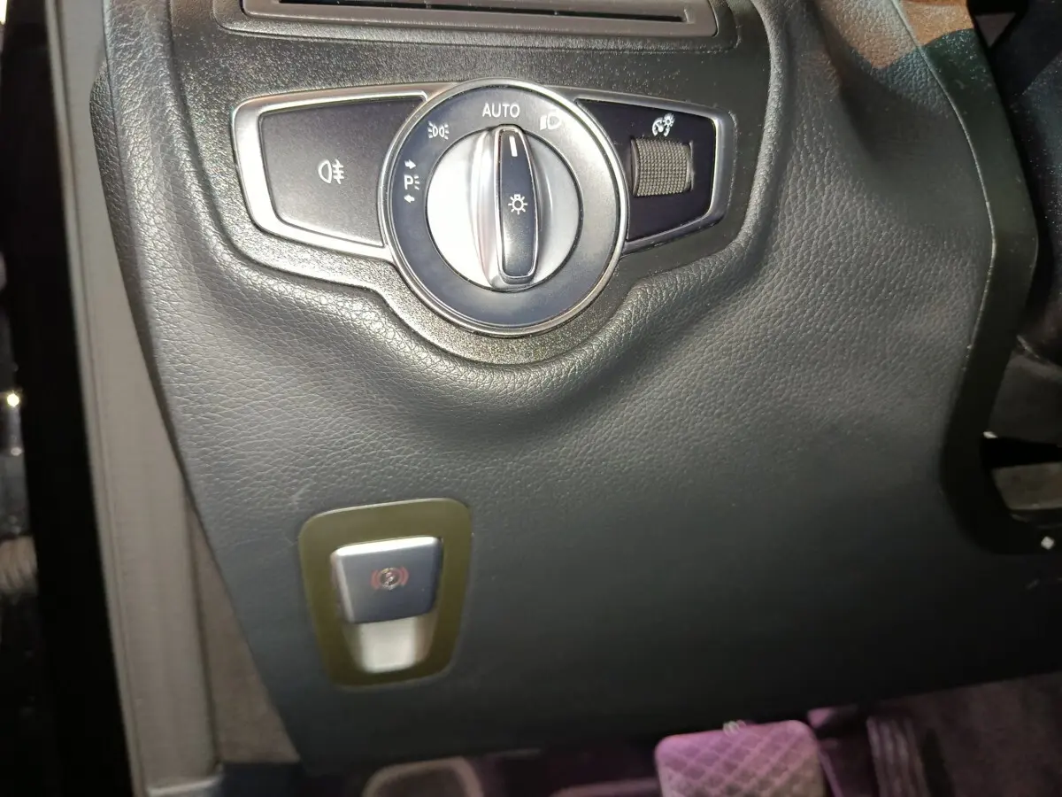 Gros plan sur le bouton des phares et frein à main électrique dans l'habitacle noir du Mercedes GLC 300 e Business Line 2020.