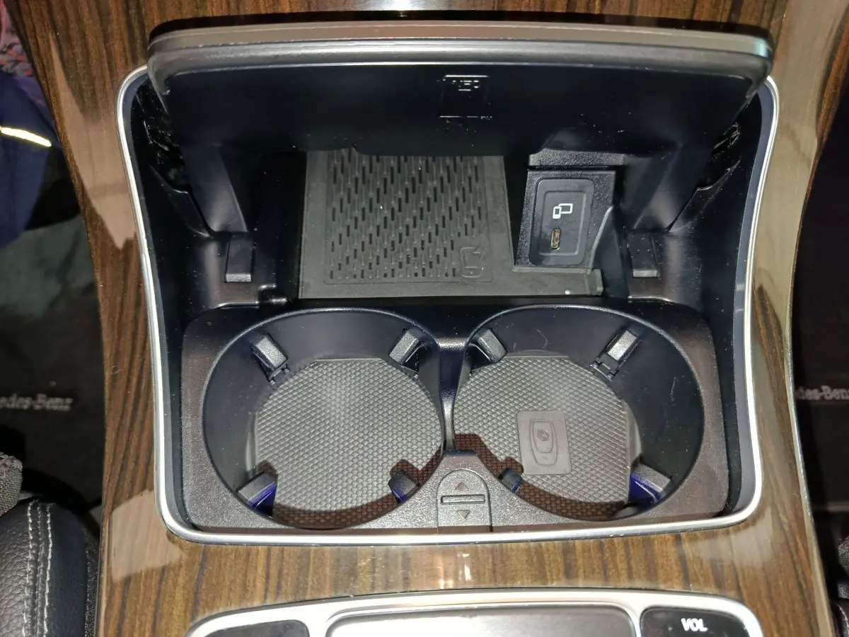 Gros plan sur les porte-gobelets et prise USB dans la console centrale en bois du Mercedes GLC 300 e noir.