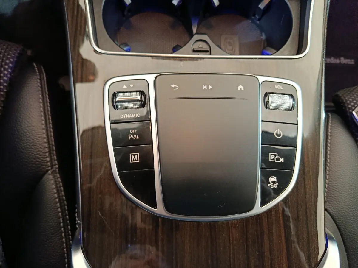Gros plan sur la console centrale en bois sombre du Mercedes GLC 300 e Business Line avec pavé tactile et commandes multifonctions.