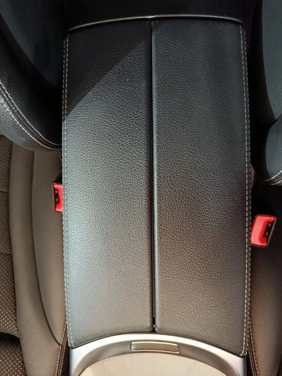 Détail de l'accoudoir central en cuir noir avec surpiqûres blanches dans l'habitacle du Mercedes GLC 300 e 2020.