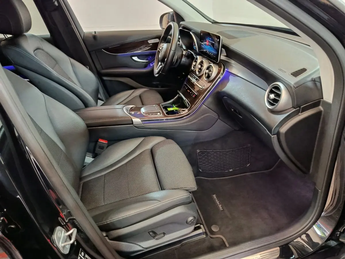 Intérieur avant droit d’un Mercedes GLC 300 e Business Line 2020 noir, avec tableau de bord moderne et éclairage d’ambiance bleu.