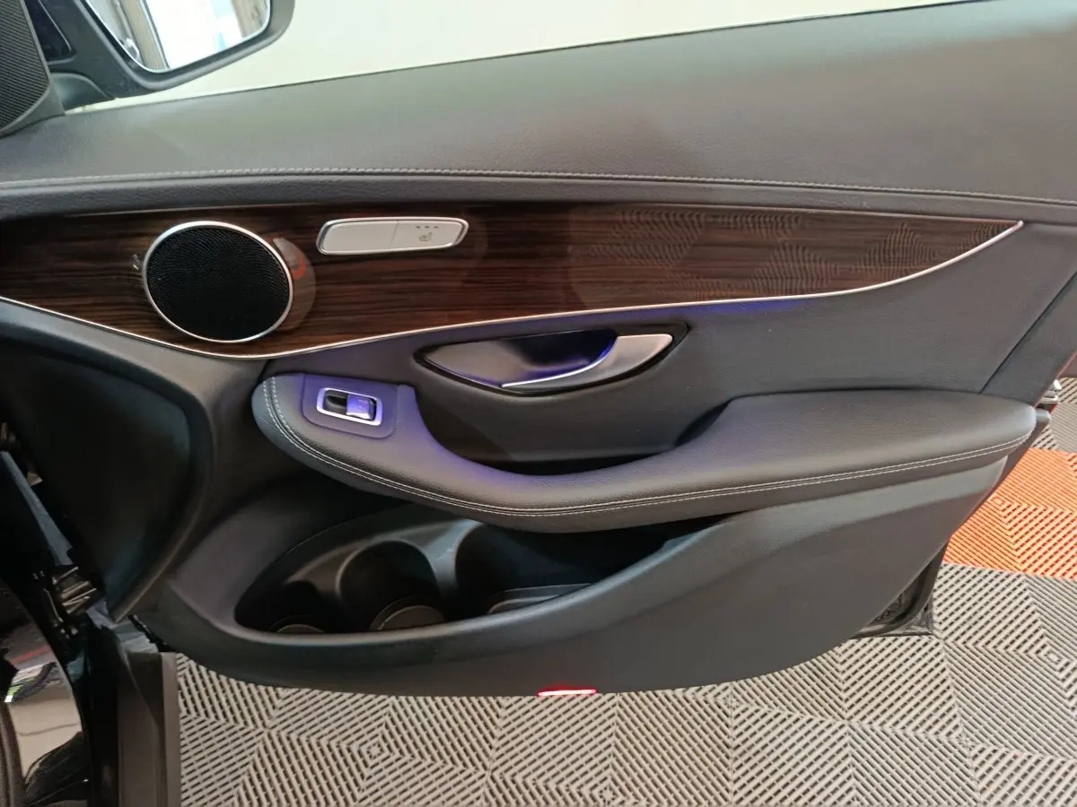 Vue intérieure côté gauche de la porte avant noire du Mercedes GLC 300 e Business Line avec garniture bois et commandes intégrées.