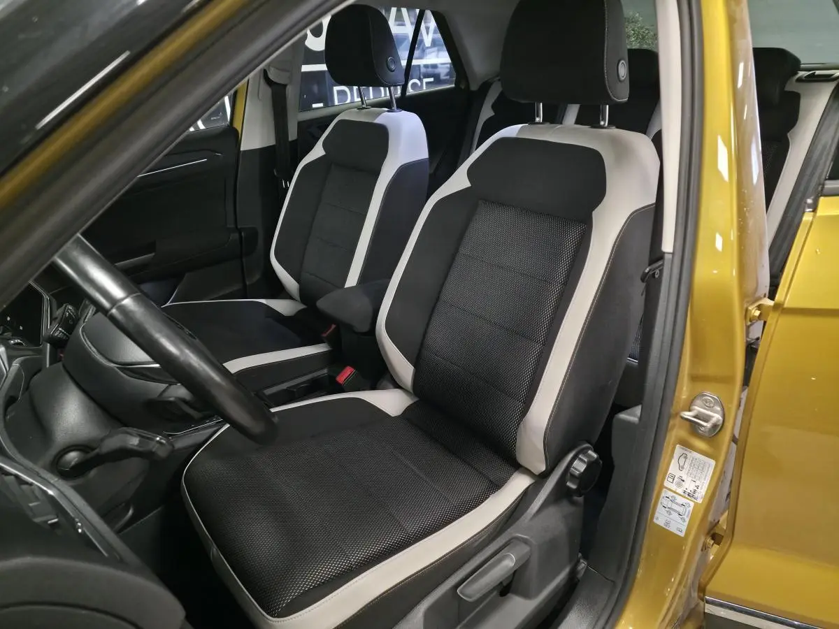 Intérieur avant du Volkswagen T-Roc 2021 avec sièges tissu noir et gris, vue côté conducteur avec porte jaune Curcuma ouverte.