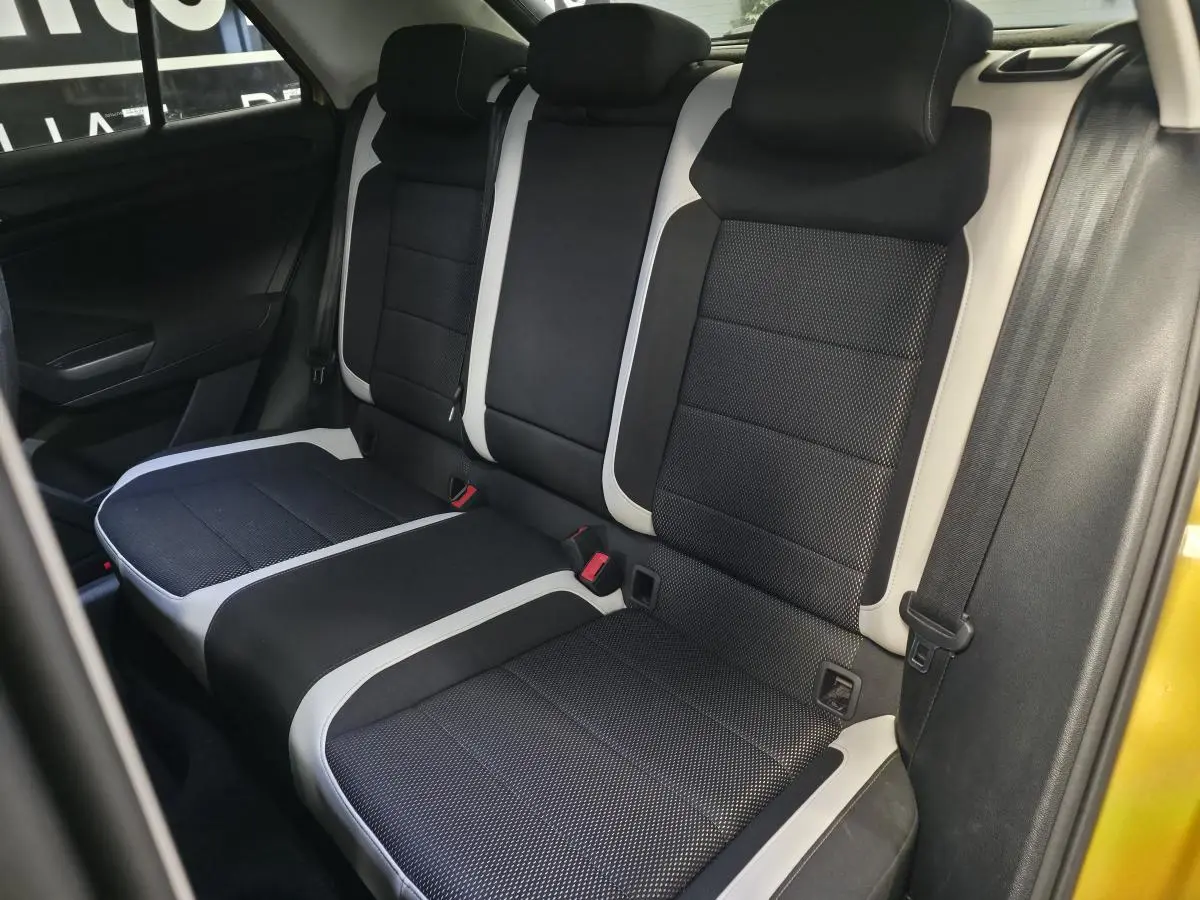 Vue latérale intérieure montrant la banquette arrière en tissu noir avec surpiqûres blanches du Volkswagen T-Roc orange 2021.