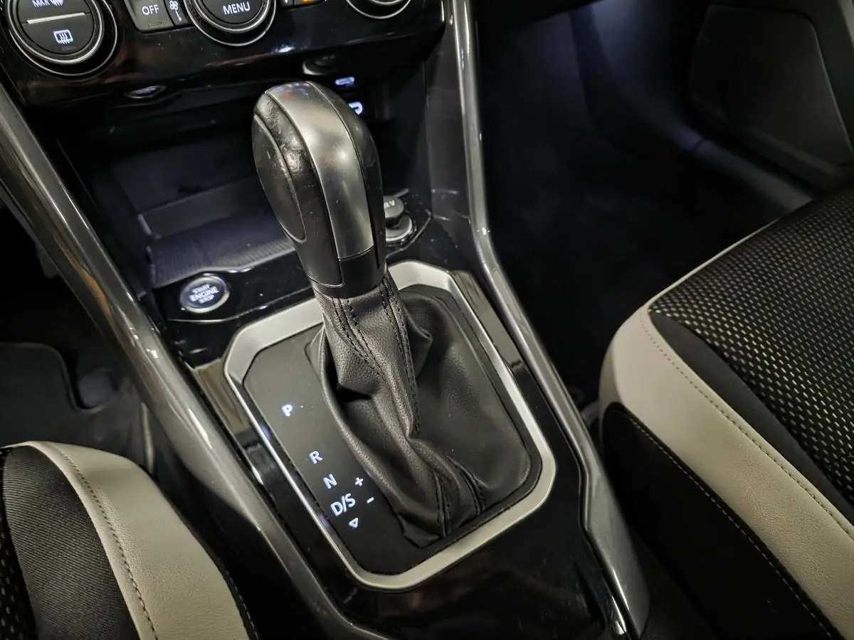 Le levier de vitesses automatique noir du Volkswagen T-Roc 2.0 TDI 2021 avec console brillante et sièges bicolores.