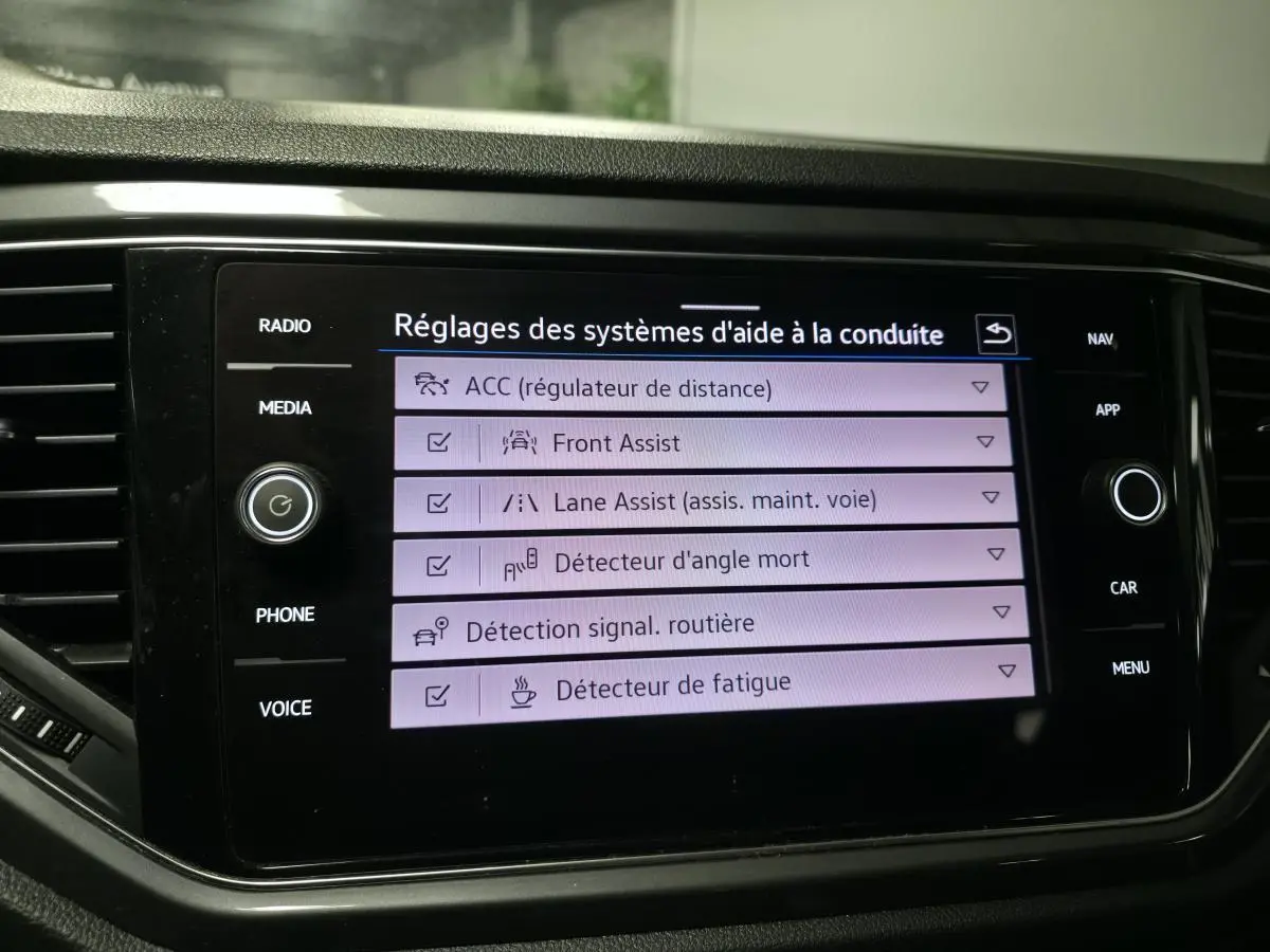 Écran tactile central du Volkswagen T-Roc affichant les réglages des aides à la conduite avec interface noire brillante