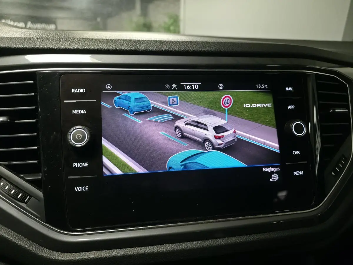 Écran tactile intérieur montrant l'assistance à la conduite avec un SUV gris en vue arrière sur la route virtuelle