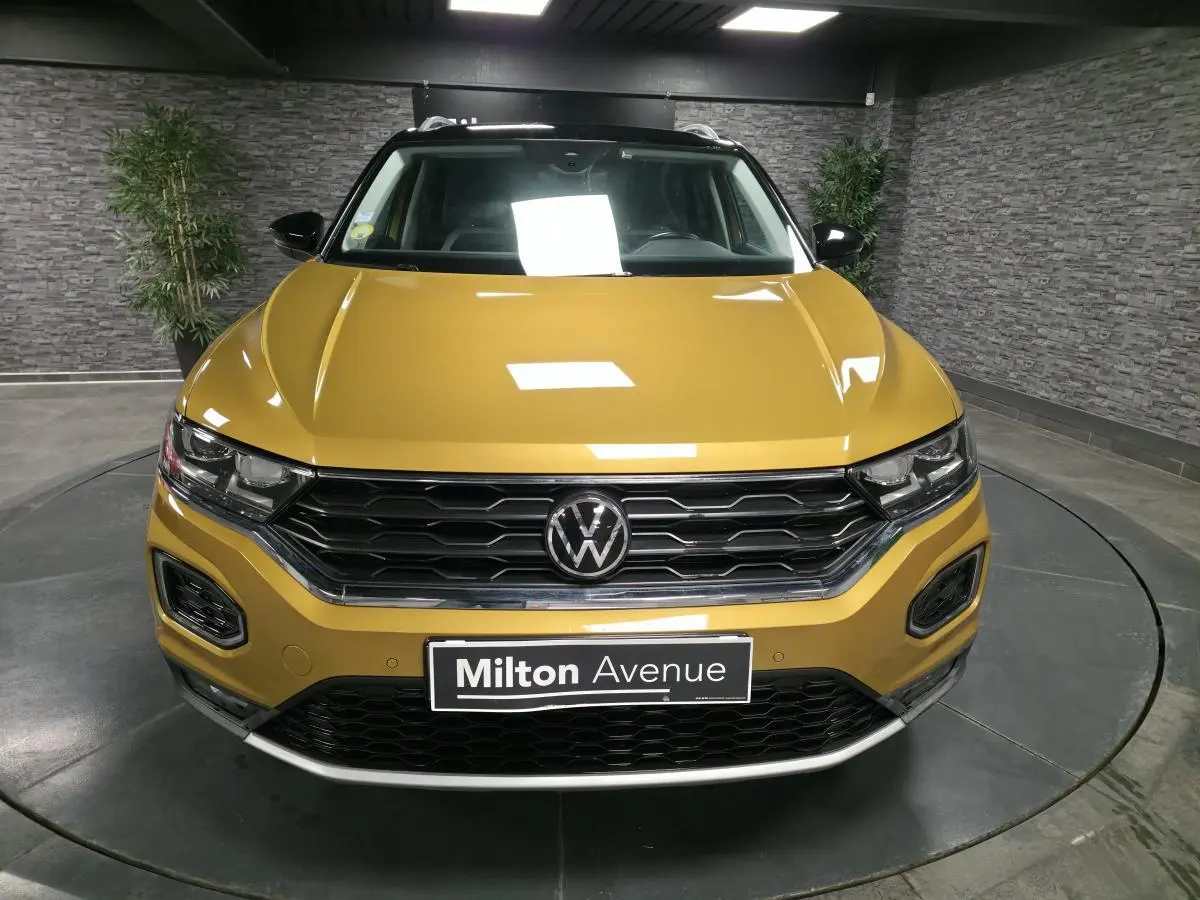 Vue frontale d'un Volkswagen T-Roc 2021 jaune curcuma avec calandre noire et toit contrastant noir.