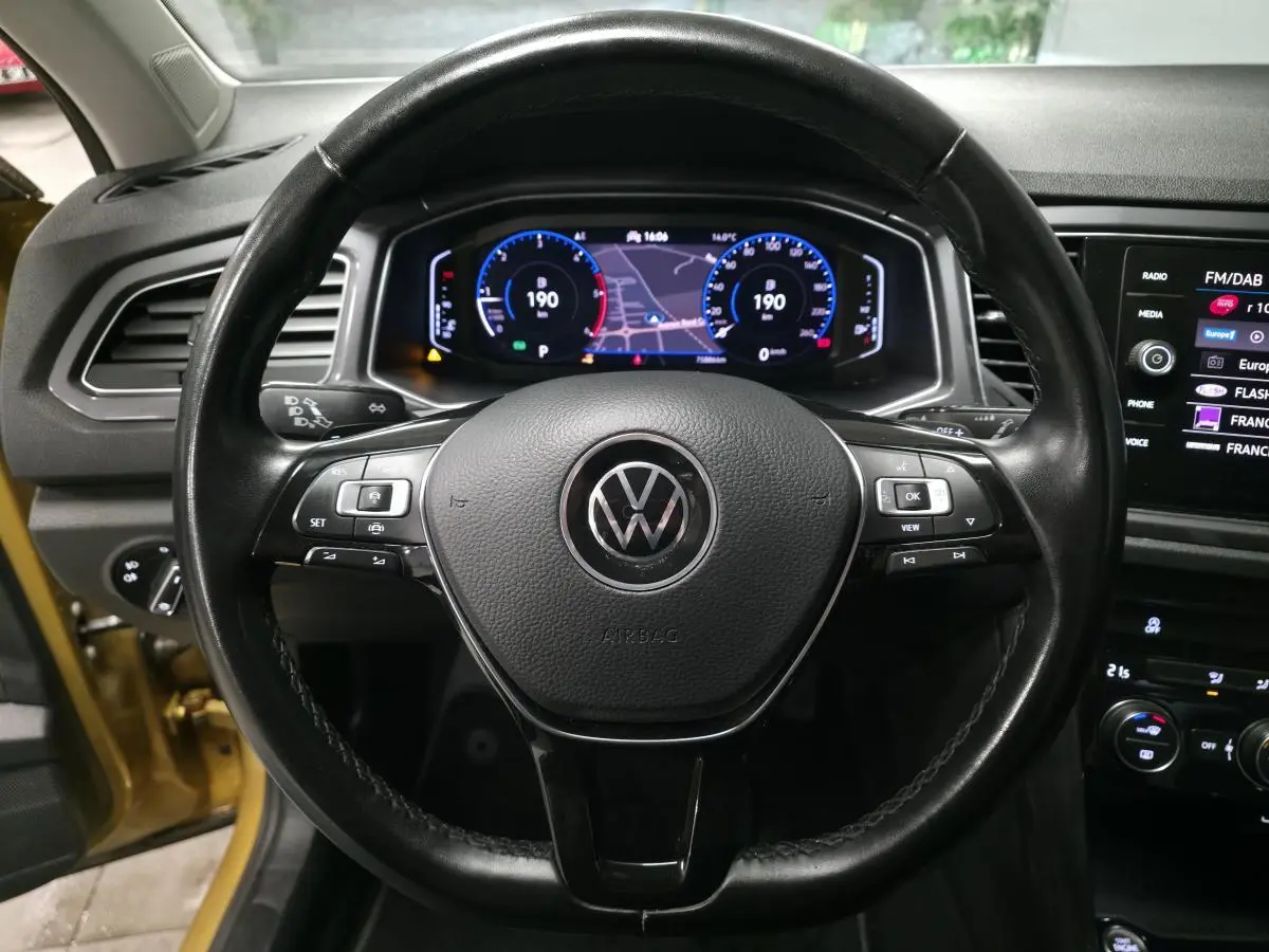 Vue centrée sur le volant en cuir noir du Volkswagen T-Roc 2021 avec tableau de bord numérique et écran tactile.
