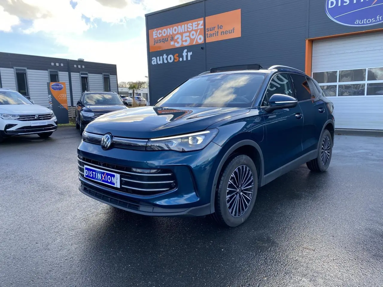 Volkswagen Tiguan 1.5 eHybrid bleu nuit en 3/4 avant droit, avec jantes alliage et calandre moderne sur parking.