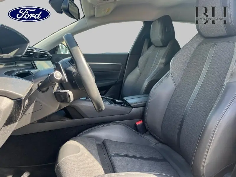 Vue intérieure côté conducteur du Peugeot 508 SW 2021, sièges en tissu et cuir gris avec volant cuir.
