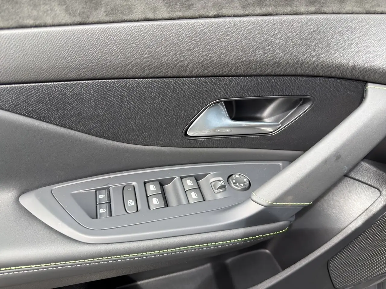 Détail de la porte côté gauche de la Peugeot 308 gris Selenium, avec commandes de vitres et surpiqûres vert Adamite.