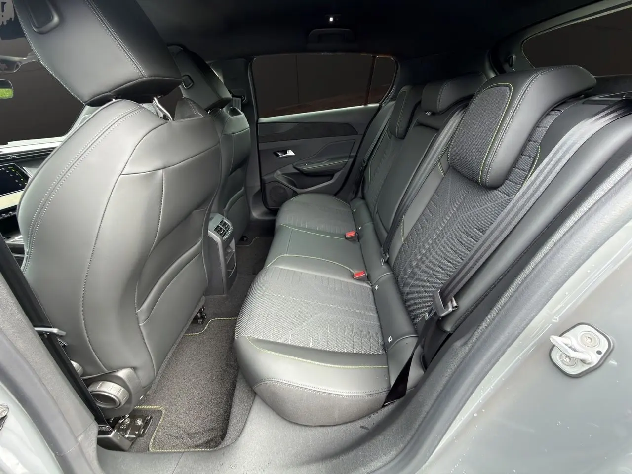 Vue côté droit de l'habitacle arrière gris sélénium de la Peugeot 308 GT 2026 avec sellerie tissu et surpiqûres vertes.