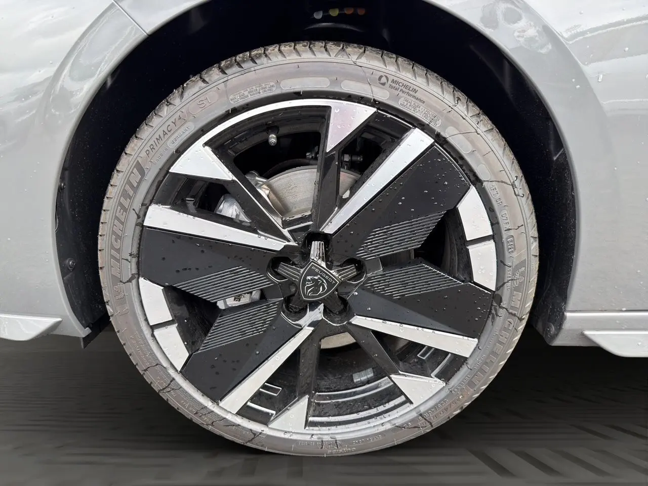 Gros plan sur la jante alliage 18'' bi-ton noir et argent avec logo Peugeot, sur roue avant droite gris selenium.