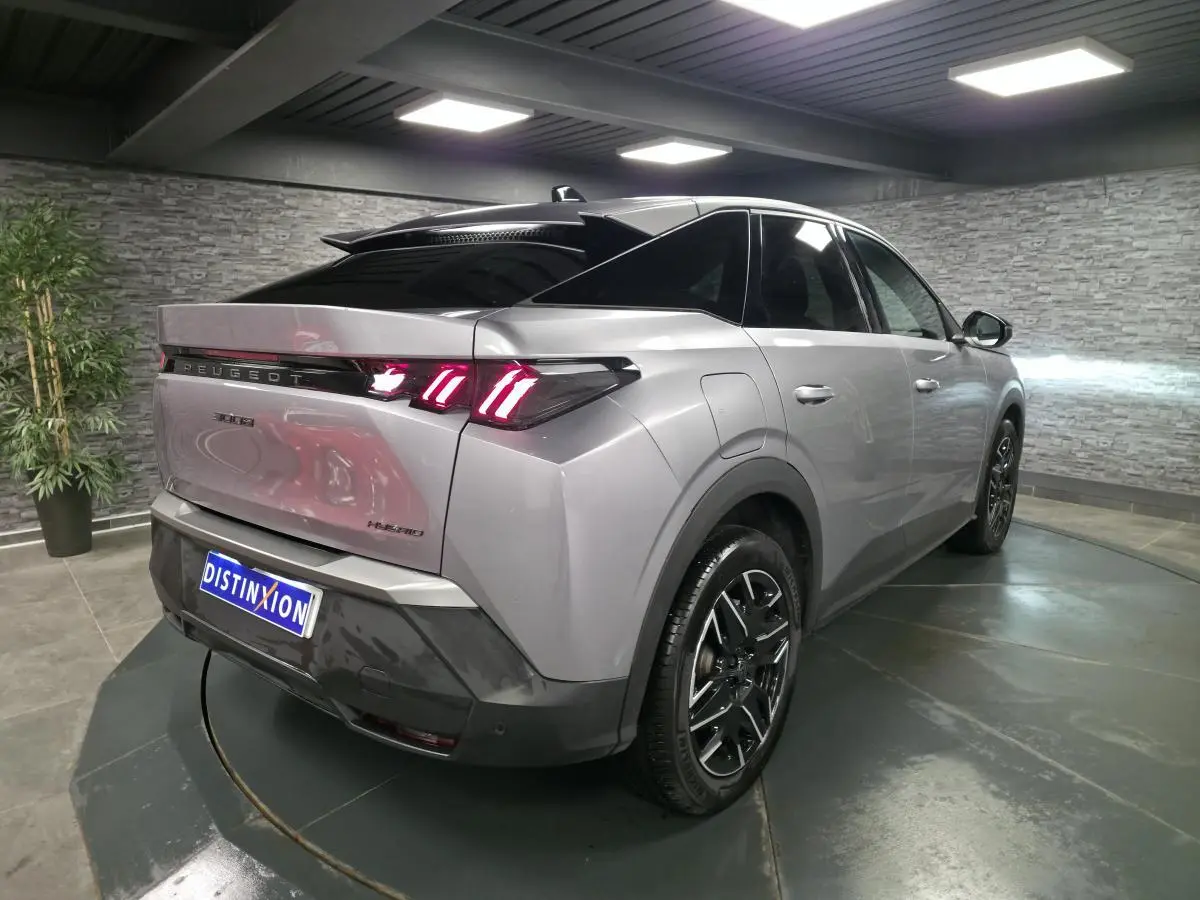 Vue 3/4 arrière droit d’un Peugeot 3008 hybride gris métallisé avec feux arrière LED en forme de griffes et jantes alliage noires.