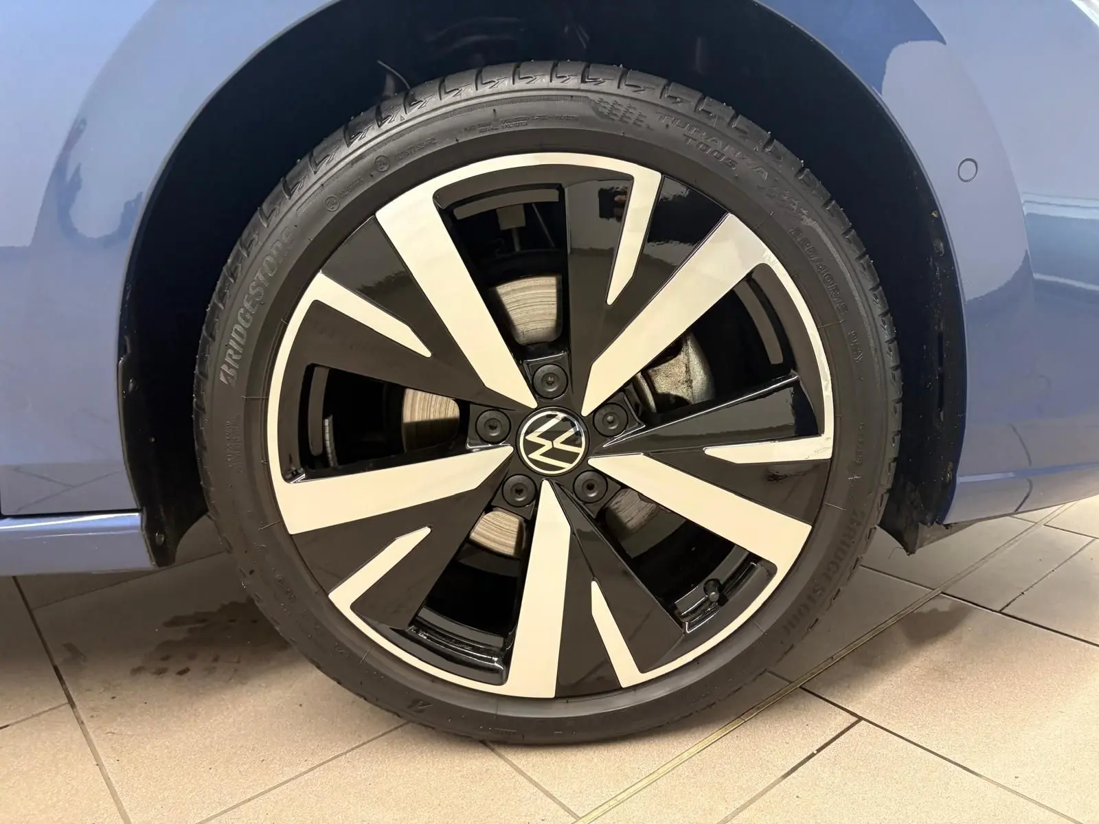 Gros plan sur la jante alliage 18'' Catania bicolore noir et argent du Volkswagen Golf Bleu Anémone côté gauche.