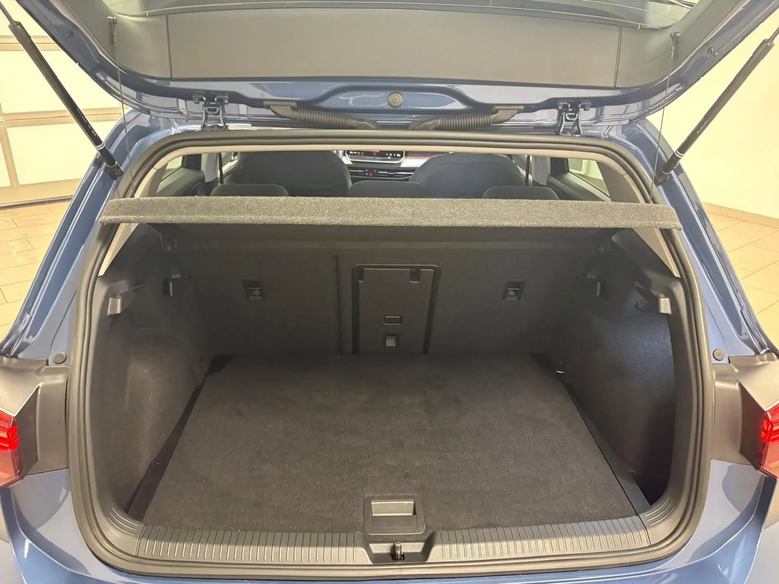 Vue arrière du coffre ouvert d'une Volkswagen Golf 1.5 eTSI 116 DSG7 Bleu Anémone, intérieur spacieux et propre.