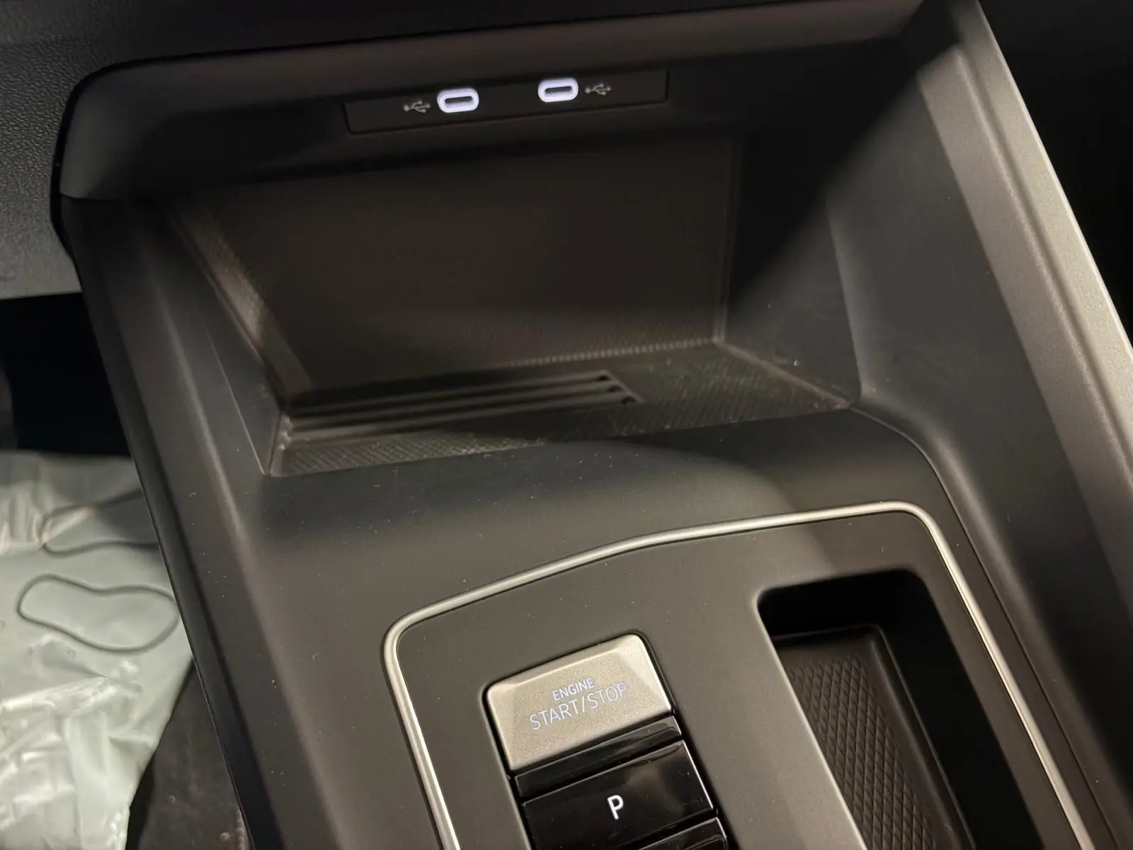 Gros plan sur la console centrale de la Volkswagen Golf 1.5 eTSI 116 DSG7, avec bouton start/stop et rangement noir mat.