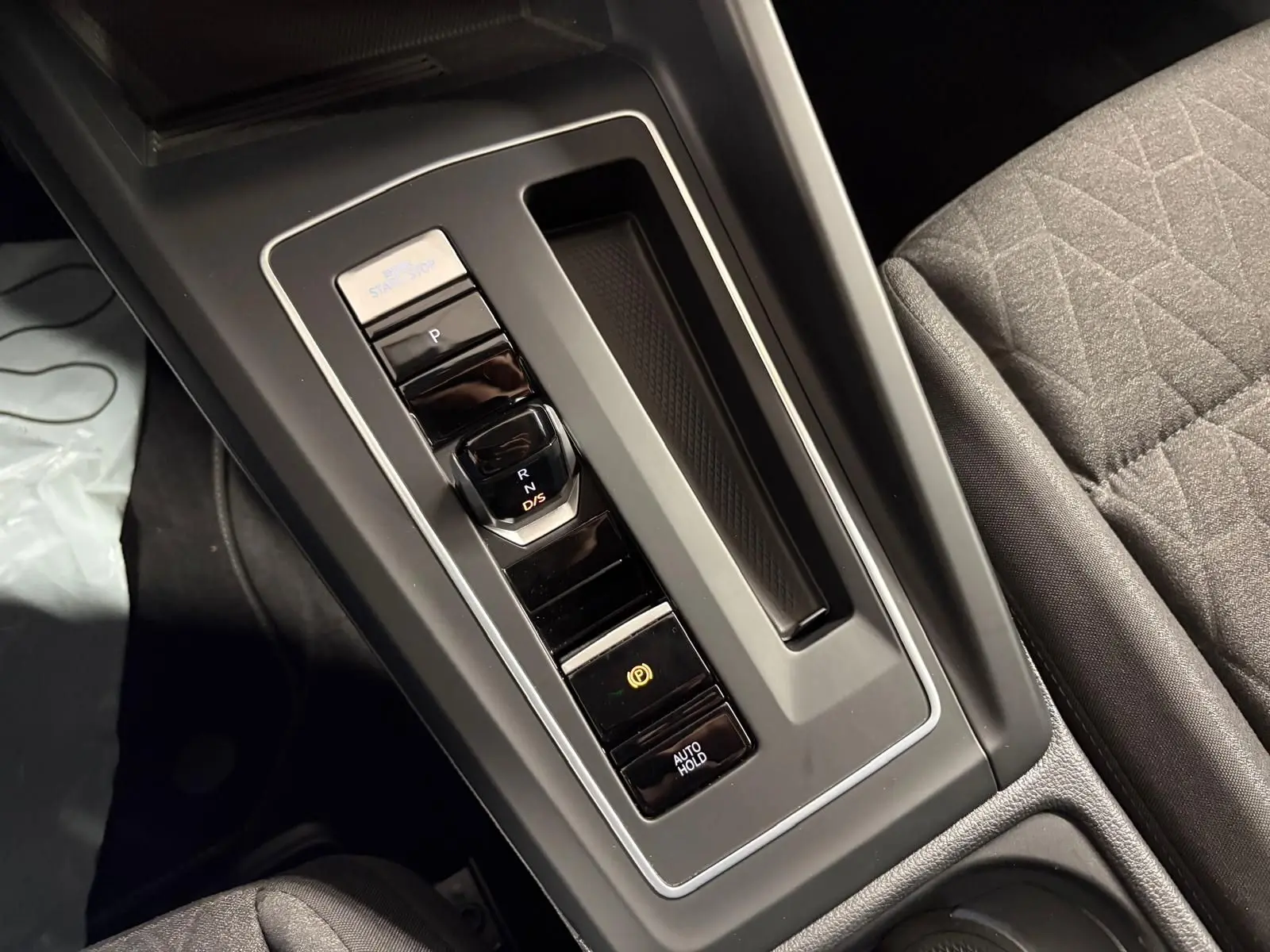 Gros plan sur la console centrale de la Volkswagen Golf 1.5 eTSI 116 DSG7, montrant la commande de boîte auto et frein électronique.