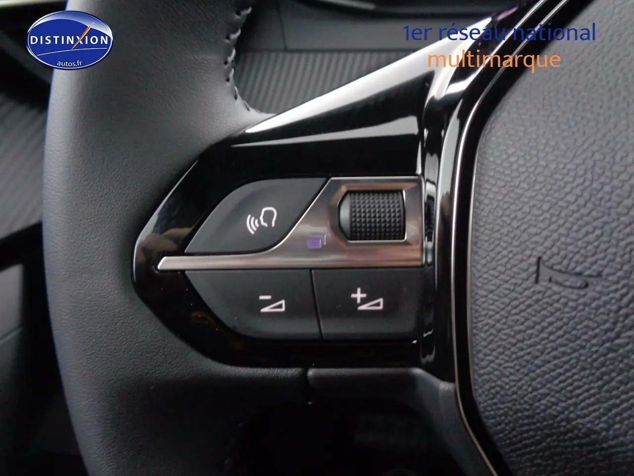 Gros plan sur les commandes du volant côté gauche du Peugeot 2008 rouge Elixir Metal, version 2023.