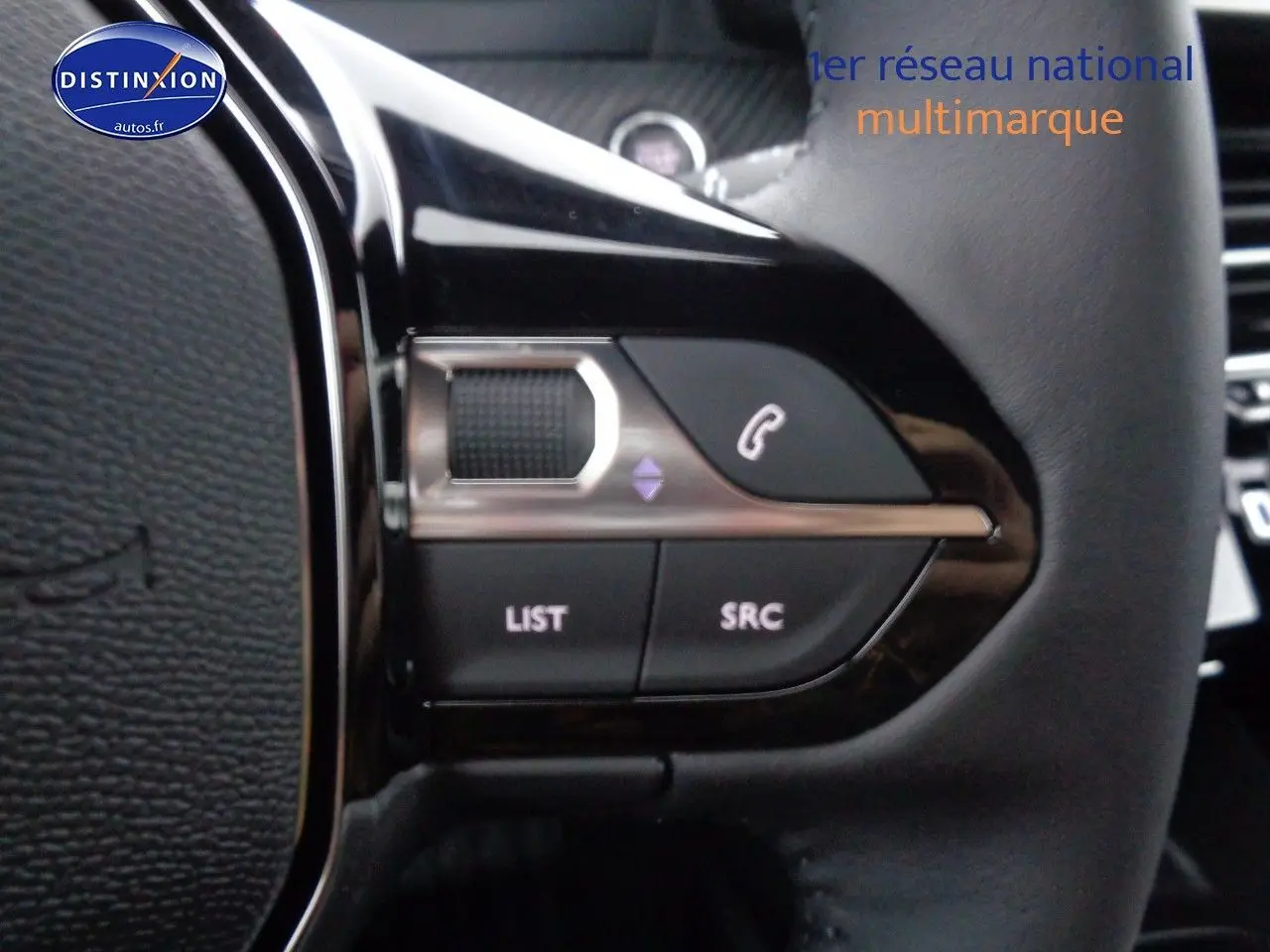 Gros plan sur les commandes du volant d'une Peugeot 2008 rouge Elixir Metal, boutons pour téléphone et liste audio.