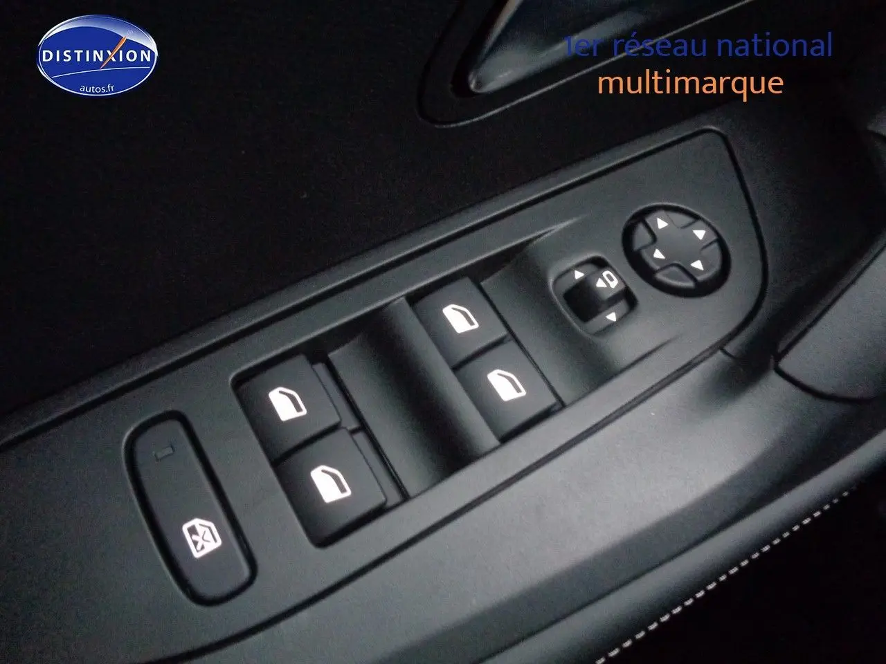 Gros plan sur les commandes des vitres électriques et réglages des rétroviseurs côté conducteur d'un Peugeot 2008 rouge Elixir Metal.