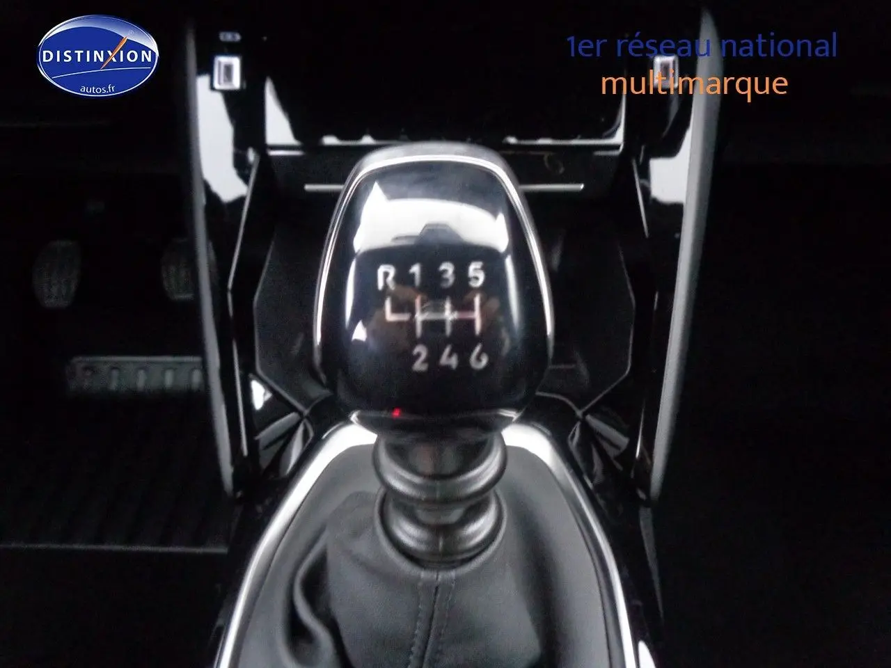 Le levier de vitesses manuel en gros plan dans l'habitacle noir brillant d'une Peugeot 2008 rouge Elixir Metal 2023.