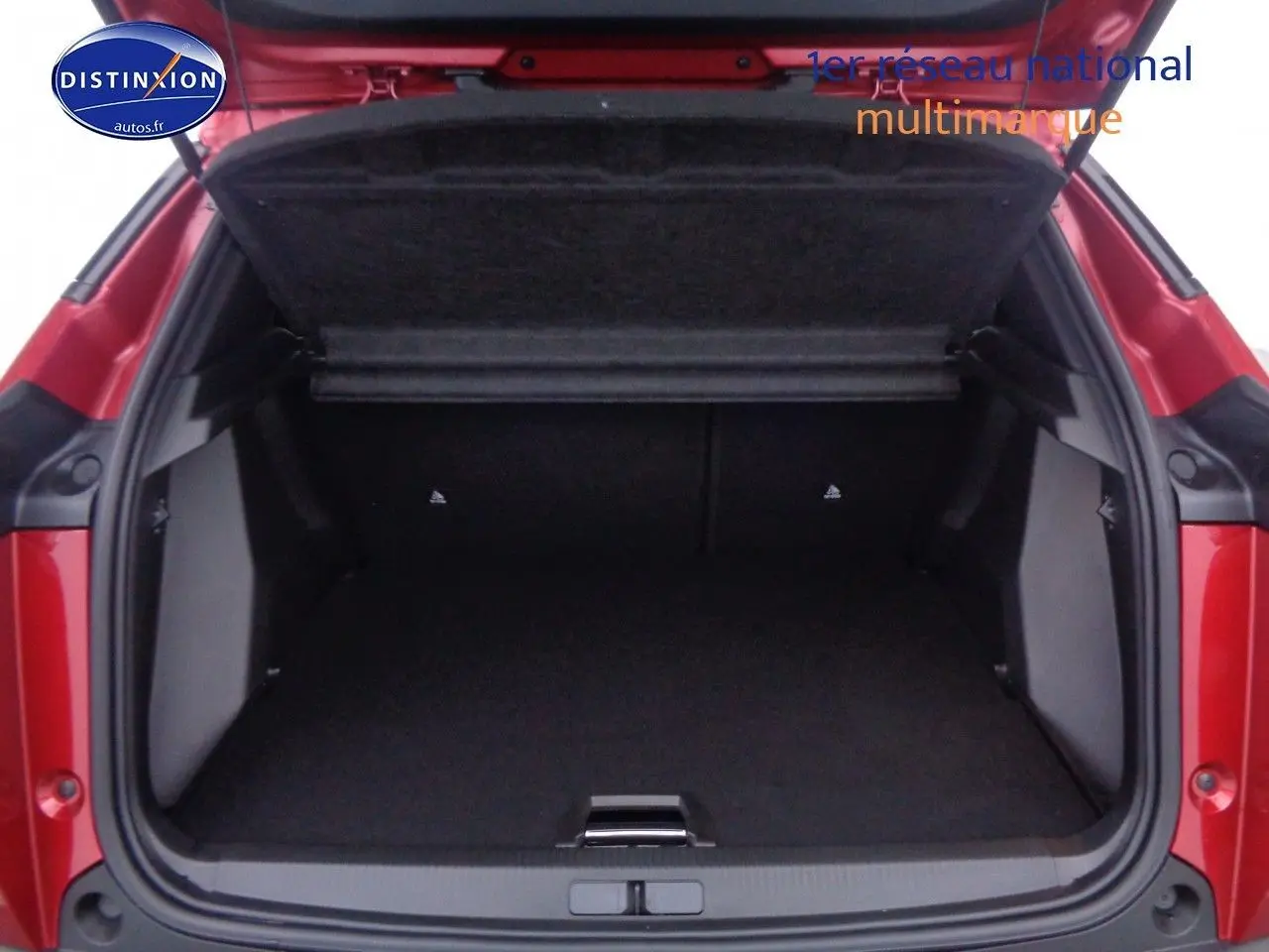 Coffre ouvert vu de l'arrière d'un Peugeot 2008 rouge Elixir Metal, montrant l'espace de chargement vide.