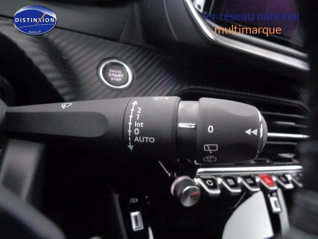 Gros plan sur la commande d’essuie-glace du Peugeot 2008 rouge Elixir Metal, avec bouton start visible en arrière-plan.