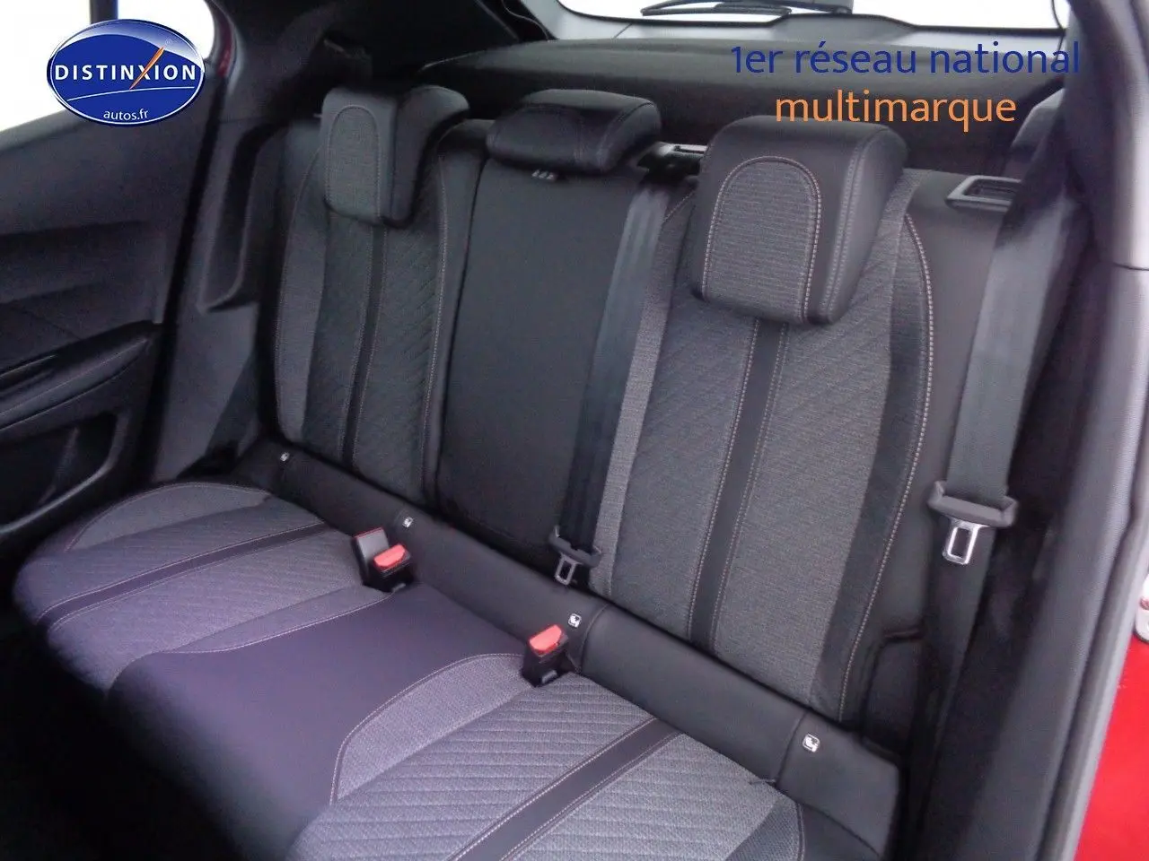 Vue latérale du siège arrière en tissu gris et noir du Peugeot 2008 rouge Elixir Metal, avec ceintures de sécurité visibles.