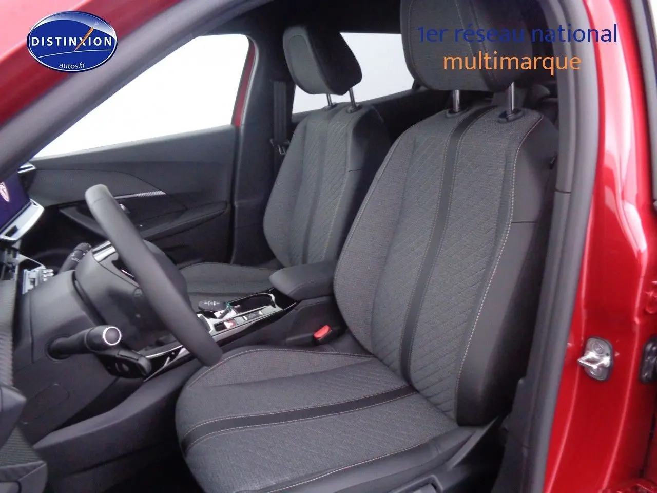 Intérieur avant droit d'une Peugeot 2008 rouge Elixir Metal avec sièges tissu gris et console centrale moderne.