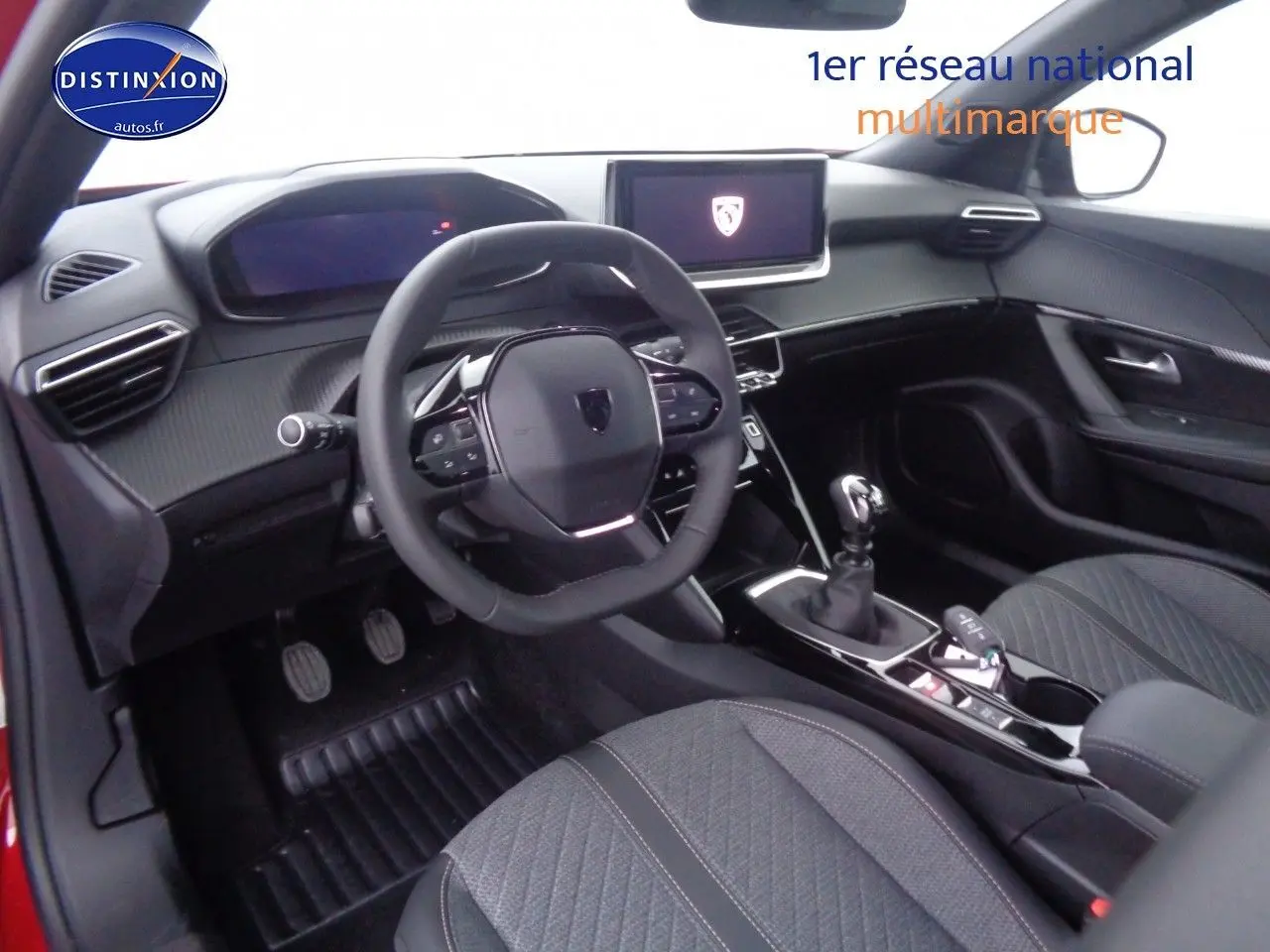 Vue intérieure du poste de conduite du Peugeot 2008 rouge Elixir avec volant multifonction et boîte manuelle.