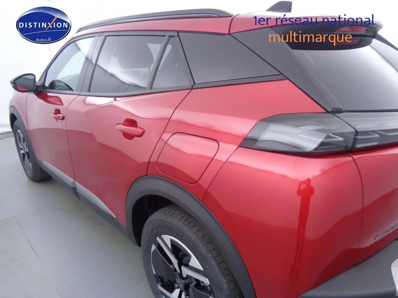 Vue 3/4 arrière gauche d'un Peugeot 2008 rouge Elixir Metal avec toit noir et jantes bi-ton.