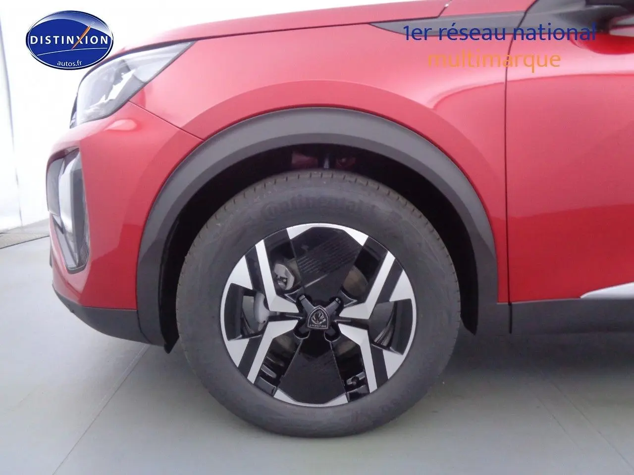 Gros plan sur la roue avant gauche du Peugeot 2008 rouge Elixir Metal avec jante bi-ton noire et argentée.