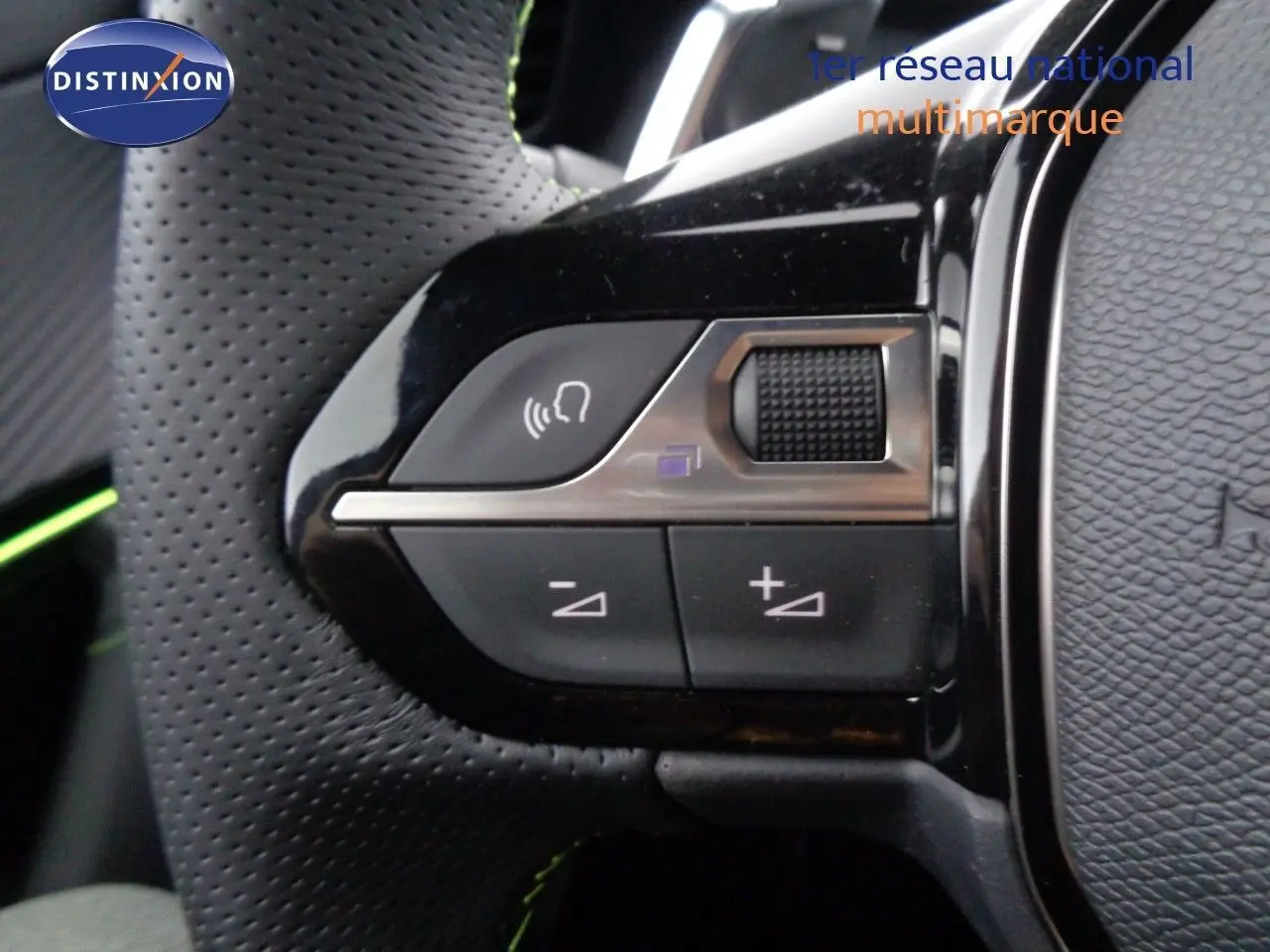 Gros plan sur les commandes vocales et volume du volant en cuir perforé noir du Peugeot 2008 GT 2023.