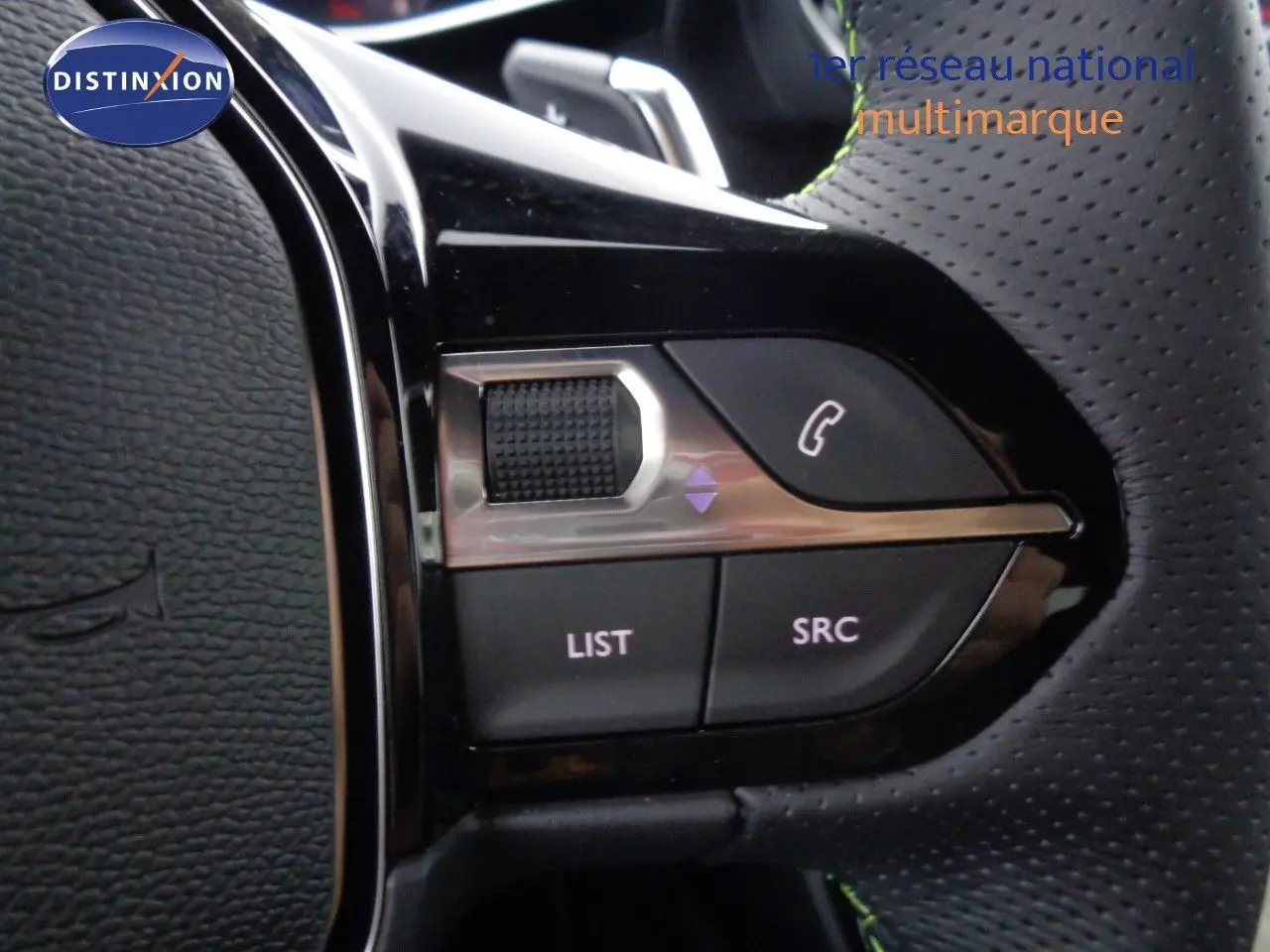 Gros plan sur les commandes du volant en cuir perforé noir de la Peugeot 2008 GT gris Artense métal avec toit noir.