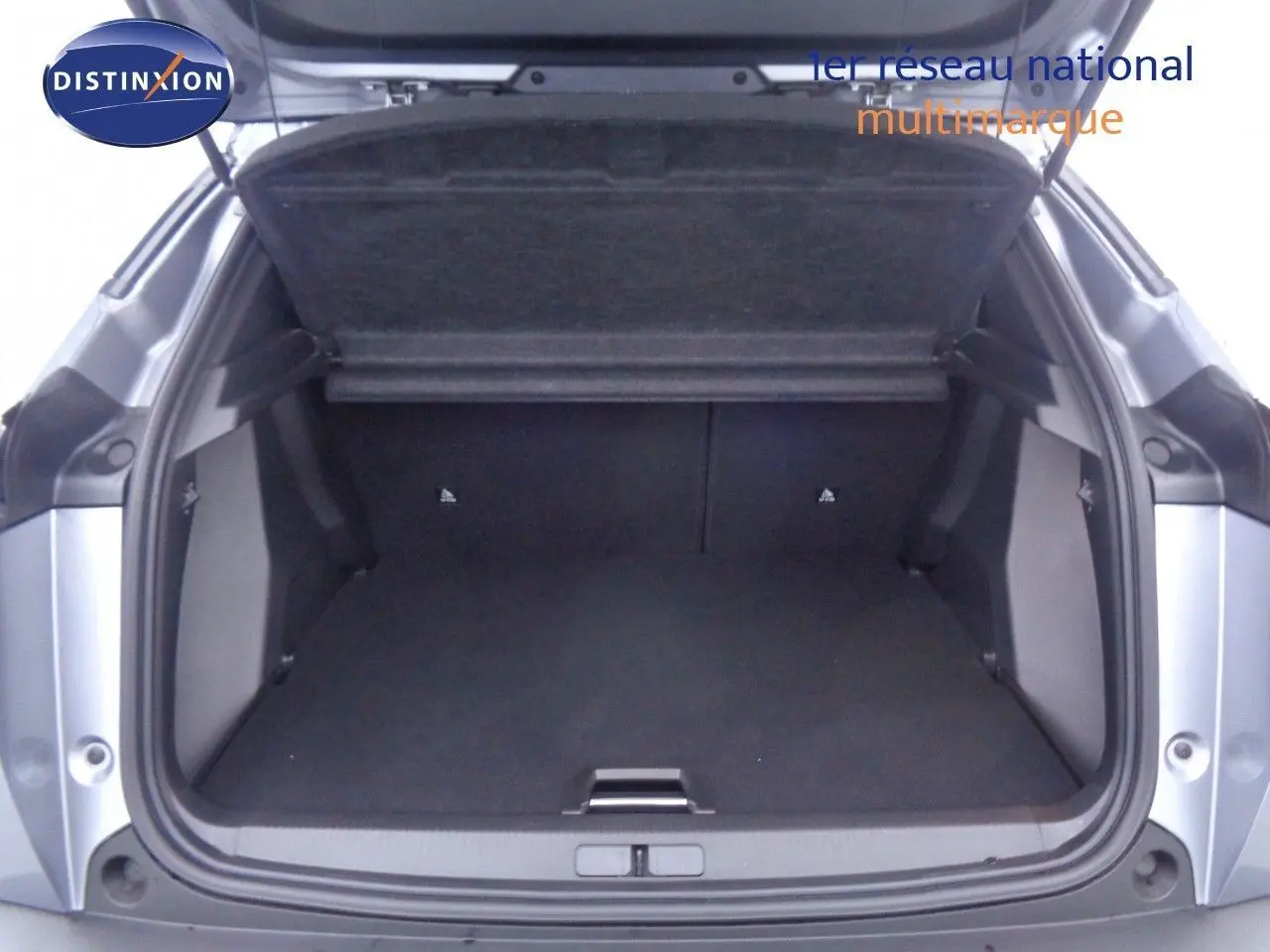 Coffre ouvert en vue arrière d'une Peugeot 2008 gris Artense métal avec toit noir, montrant un espace de chargement vide.
