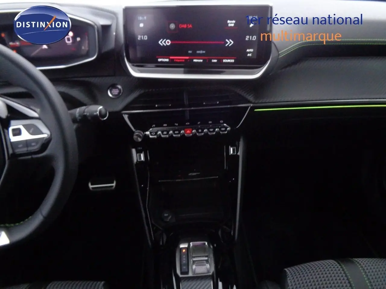Vue intérieure centrée sur la console et le tableau de bord du Peugeot 2008 gris avec détails verts et écran tactile.