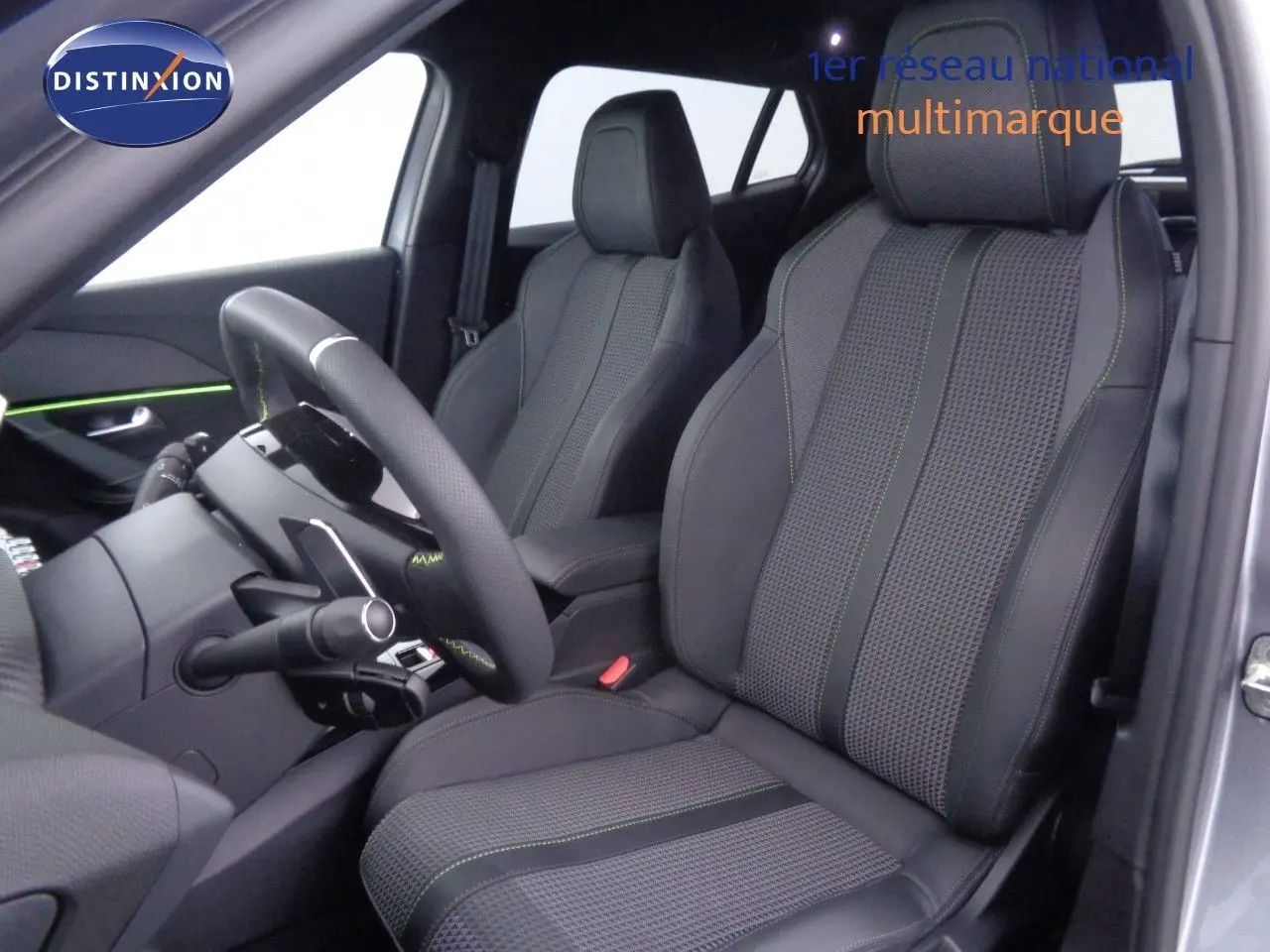 Vue intérieure côté conducteur du Peugeot 2008 gris Artense avec sièges en cuir noir et surpiqûres vertes.